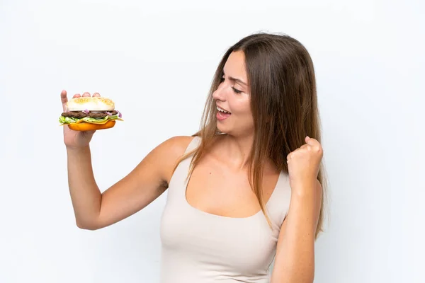 Jonge Mooie Vrouw Houden Een Hamburger Geïsoleerd Witte Achtergrond Vieren — Stockfoto
