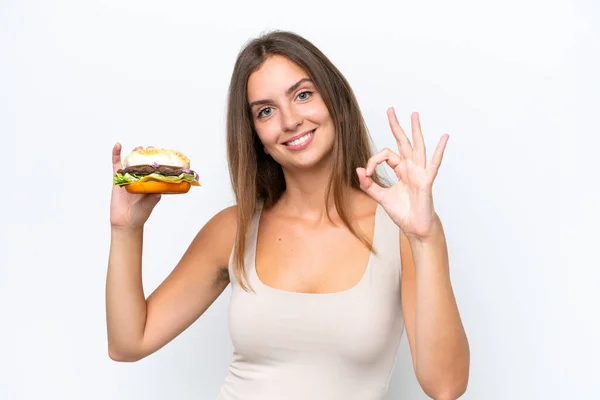 Młoda Ładna Kobieta Trzyma Hamburgera Izolowane Białym Tle Pokazuje Znak — Zdjęcie stockowe