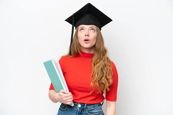 Fiatal Egyetemi Diplomás Elszigetelt Fehér Háttér Néz Fel Meglepett Arckifejezéssel — Stock Fotó