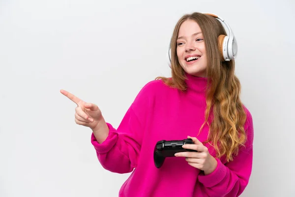 年轻漂亮的女人在玩一个独立于白色背景的电子游戏控制器 手指指向旁边 并展示了一个产品 — 图库照片