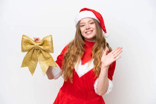 年轻的高加索女人 身穿圣诞礼服 手持白色背景的圣诞弓 手牵着手愉快地打招呼 — 图库照片