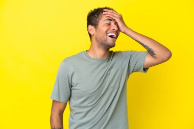 Sarı arka planda izole edilmiş yakışıklı Brezilyalı adam çok gülümsüyor.