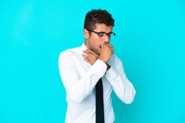 Mavi arka planda kalan Brezilyalı genç adam öksürükten muzdarip ve kötü hissediyor.