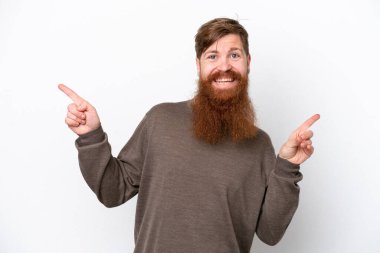 Beyaz arka planda sakallı kızıl saçlı adam parmak uçlarını işaret ediyor ve mutlu.