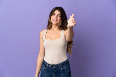 Mor arka planda izole genç beyaz kadın para hareketi yapıyor.