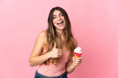 Kornet dondurması olan beyaz bir kadın pembe arka planda izole edilmiş bir şekilde baş parmak hareketi yapıyor.