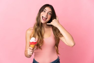 Pembe arka planda izole edilmiş kornet dondurmalı beyaz bir kadın telefon jesti yapıyor. Bana geri dönüş işareti ver.