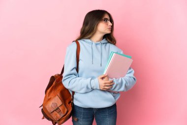 Pembe arka planda izole edilmiş genç bir bayan yan tarafa bakıyor.