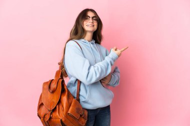 Pembe arka planda izole edilmiş genç bir bayan parmak kenarı işaret ediyor.