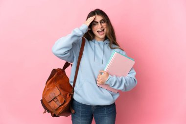Pembe arka planda izole edilmiş genç bayan öğrenci. Sürpriz bir ifadeyle.