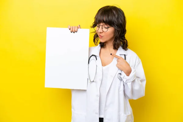年轻的医生拉汀女士 背景是黄色的 手里拿着一张空的标语牌 望着它 — 图库照片