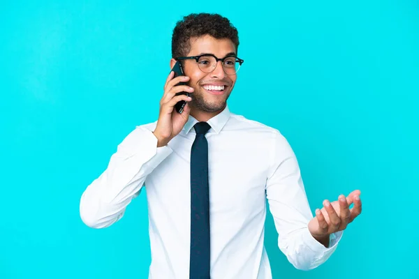青い背景で孤立した若いビジネスブラジル人男性誰かと携帯電話との会話を保ちます — ストック写真