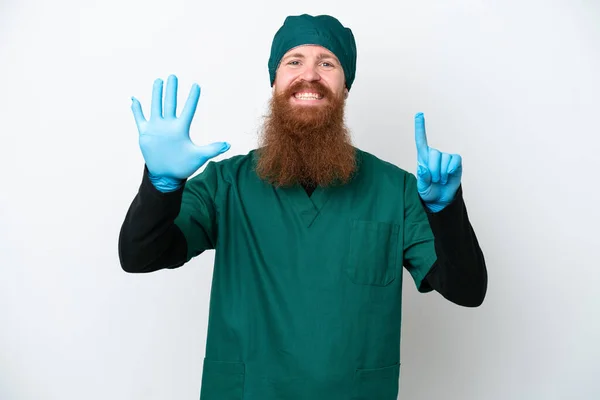 Stock image Surgeon redhead man in green uniform isolated on white background counting six with fingers