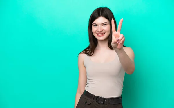 緑の背景の笑顔と勝利の兆候を示す上で隔離された若いロシア人女性 — ストック写真
