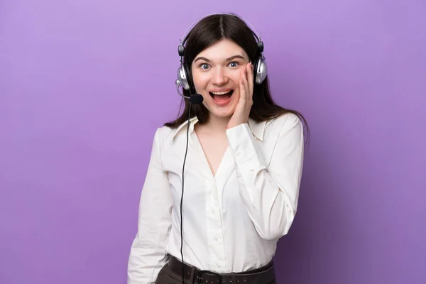 Telemarketer Russian woman working with a headset isolated on purple background with surprise and shocked facial expression