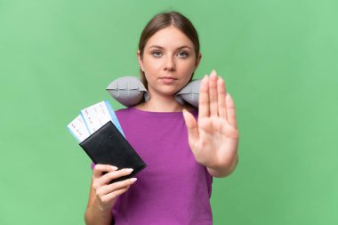 Şişirilebilir seyahat yastığı olan genç, güzel sarışın kadın izole arka planda durup jest yapıyor.