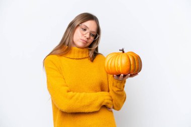 Beyaz arka planda hüzünlü bir ifadeyle kabak tutan beyaz bir kadın.