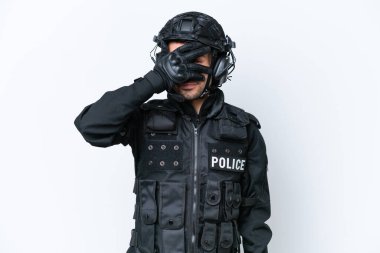 Beyaz arka planda izole edilmiş beyaz tenli beyaz bir SWAT adamı gözlerini elleriyle kapatıyor ve gülümsüyor.