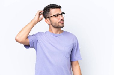 Young caucasian man isolated on white background having doubts while scratching head