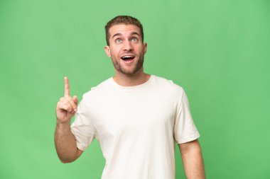 Yeşil krom arka planda izole edilmiş yakışıklı beyaz adam yukarı bakıyor ve şaşırıyor.