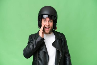 Motosiklet kasklı, yeşil renkli arka planda, şaşırmış ve şok olmuş bir yüz ifadesi olan beyaz bir genç.