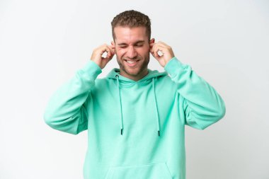 Beyaz arka planda izole edilmiş yakışıklı beyaz adam hayal kırıklığına uğramış ve kulaklarını kapatmış.