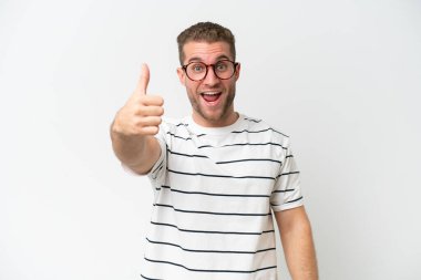 Beyaz arka planda izole edilmiş beyaz, yakışıklı beyaz bir adam. Başparmakları havada, çünkü iyi bir şey oldu.