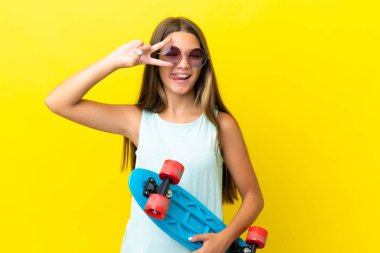 Küçük beyaz kaykaycı kız mutlu bir ifadeyle sarı arka planda izole edilmiş.