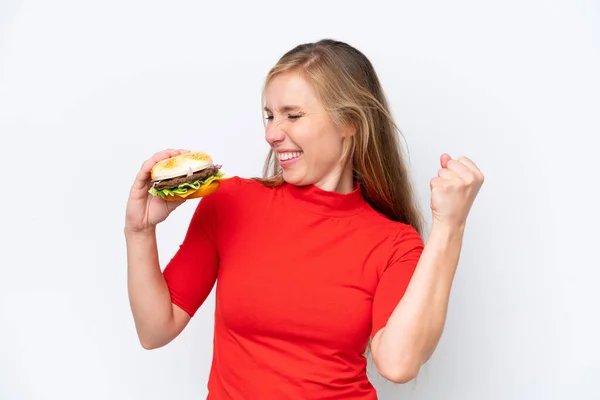 Young Blonde Woman Holding Burger Isolated White Background Celebrating Victory — Stock Photo, Image