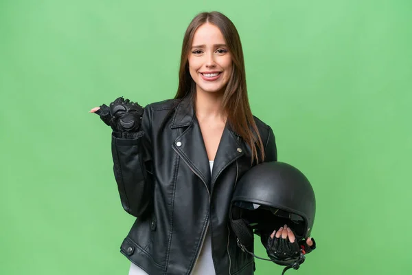 若いですかなりCaucasian女性とともにオートバイヘルメット上の隔離された背景を指す側に製品を提示します — ストック写真