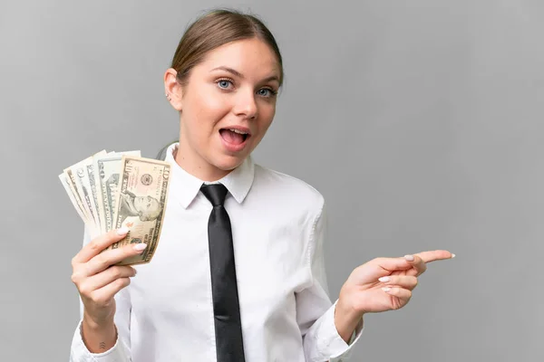 Νεαρή Λευκή Γυναίκα Επιχειρηματίας Που Κρατάει Χρήματα Απομονωμένο Υπόβαθρο Έκπληκτη — Φωτογραφία Αρχείου