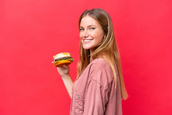 Jeune Femme Caucasienne Tenant Hamburger Isolé Sur Fond Rouge Souriant — Photo