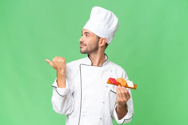Jeune Chef Caucasien Tenant Sushi Sur Fond Isolé Pointant Vers — Photo