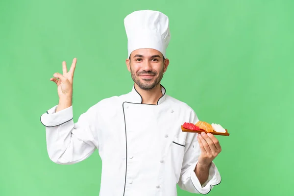Junger Kaukasischer Koch Hält Lächelnd Ein Sushi Vor Isoliertem Hintergrund — Stockfoto