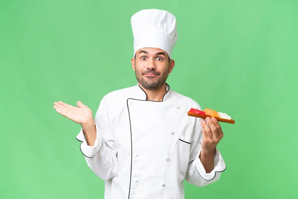 Jovem Chef Caucasiano Segurando Sushi Sobre Fundo Isolado Tendo Dúvidas — Fotografia de Stock