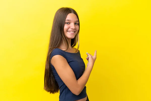 Pequena Menina Caucasiana Isolado Fundo Amarelo Apontando Para Trás — Fotografia de Stock