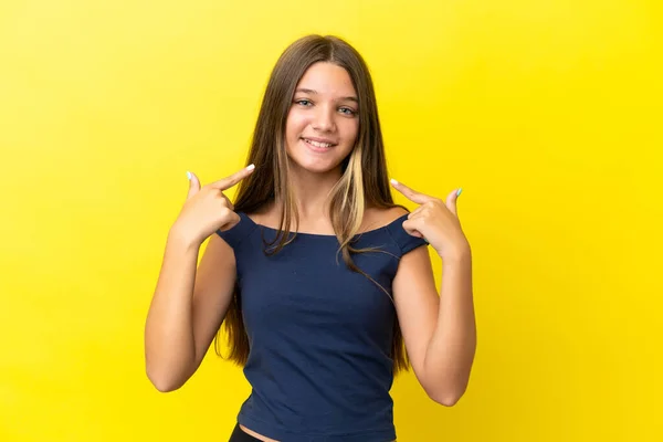 一个被黄色背景隔离的高加索小女孩举起大拇指做了个手势 — 图库照片