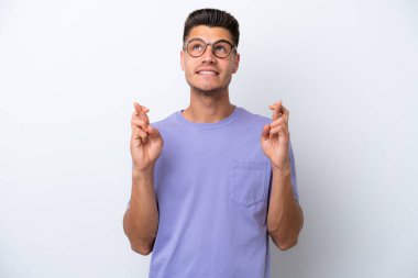 Beyaz arka planda izole olmuş genç beyaz bir adam parmaklarını çapraz yapıp en iyisini diliyor.