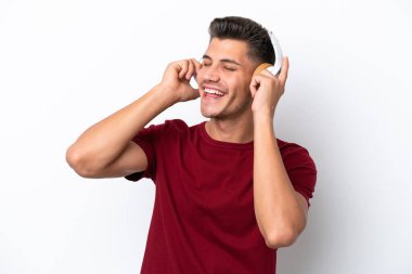 Beyaz arka planda izole edilmiş genç beyaz bir adam müzik dinliyor ve şarkı söylüyor.