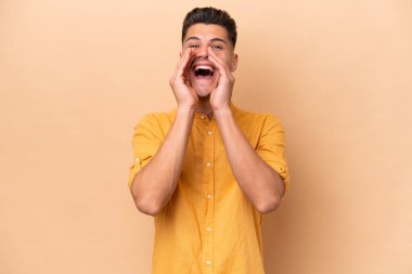 Beyazlı genç adam bej arka planda izole edilmiş bağırıyor ve bir şey duyuruyor.