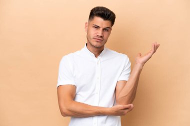 Beyazlı genç bir adam bej arka planda izole edilmiş. Şüpheleri var.