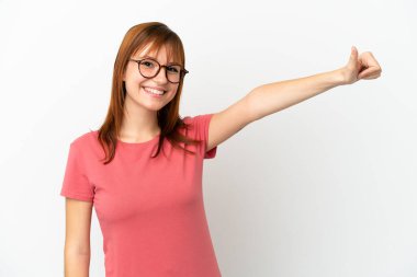 Kızıl saçlı kız beyaz arka planda izole edilmiş bir şekilde baş parmak işareti yapıyor.