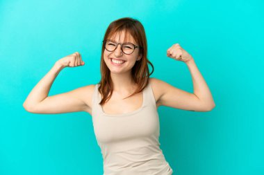 Redhead girl isolated on blue background doing strong gesture
