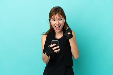 Redhead sport girl isolated on blue background surprised and sending a message