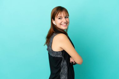 Kızıl saçlı sporcu kız mavi arka planda izole edilmiş kolları bağlı ve mutlu.