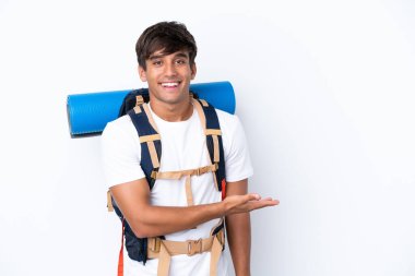 İzole edilmiş beyaz arka planda büyük bir sırt çantasıyla genç dağcı kadın gülümseyerek bir fikir sunuyor.