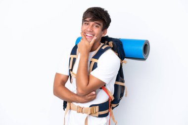İzole edilmiş beyaz arka planda büyük bir sırt çantası olan genç dağcı kadın gülümsüyor.