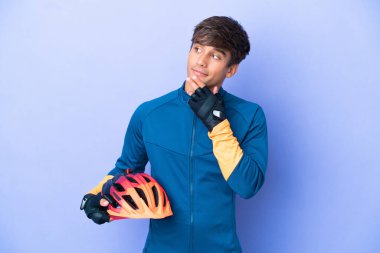 Mor arka planda izole edilmiş genç beyaz adam gülümserken yukarı bakıyor.