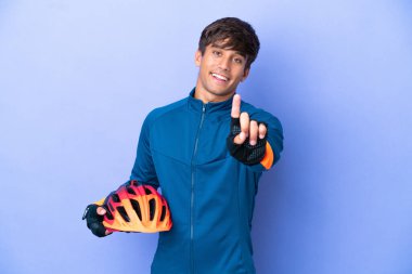 Mor arka planda izole edilmiş genç bir beyaz adam parmağını kaldırıyor ve gösteriyor.