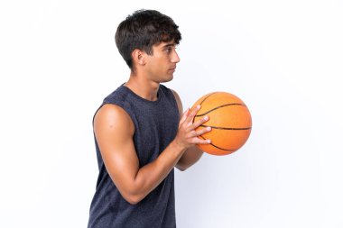 Beyaz arka planda basketbol oynayan beyaz tenli genç adam.